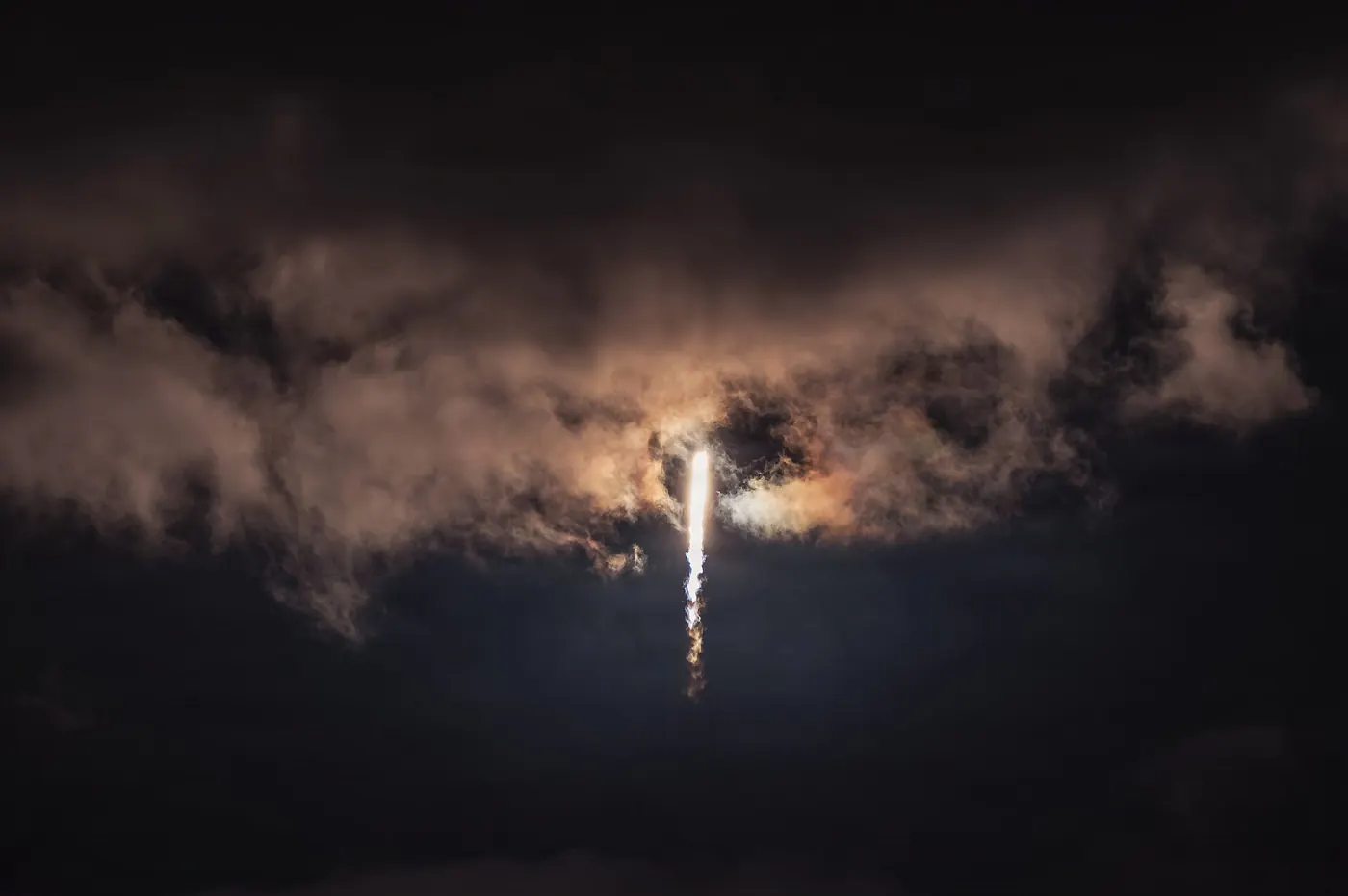 A Falcon 9 rocket launching a batch of Starlink satellites at dusk